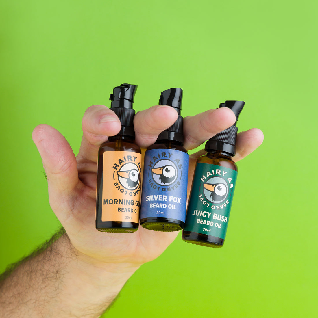 A hand holding the Hairy As Beard Oil Collection. From left to right Morning Glory, Silver Fox and Juicy Bush.