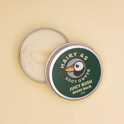 Hairy As Beard Love Beard Balm blend Juicy Bush. A 60ml grey aluminium screw top tin that is open so you can see inside. Label is green with cream coloured font. Features the Hairy As logo of a bearded duck.