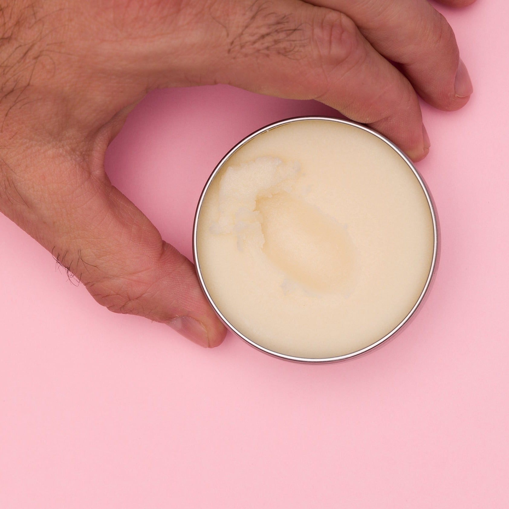 Tin of Hairy As Silver Fox Beard Butter open on pink background highlighting its creamy texture and natural ingredients for sophisticated beard grooming and nourishment.