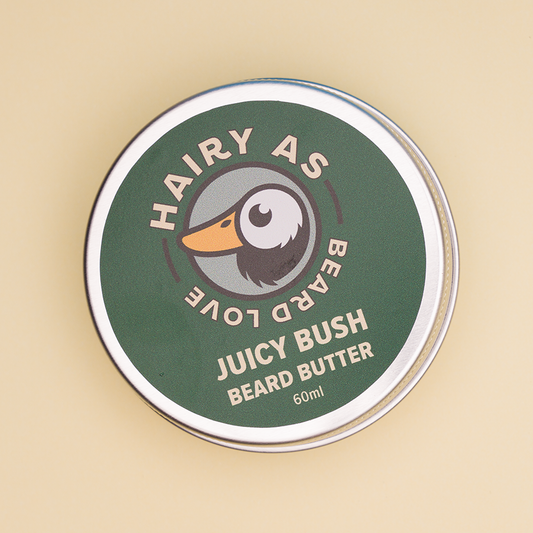 Hairy As Beard Love Beard Butter blend Juicy Bush. A 60ml grey aluminium screw top tin. Label is green with cream coloured font. Features the Hairy As logo of a bearded duck.