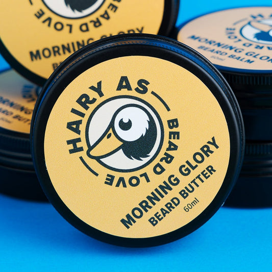 Tin of Hairy As Morning Glory Beard Butter on a blue surface. Highlights are its creamy texture and natural ingredients for optimal beard care.