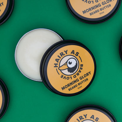 Tin of Hairy As Morning Glory Beard Butter open on a green surface highlighting its creamy texture and natural ingredients for optimal beard care.