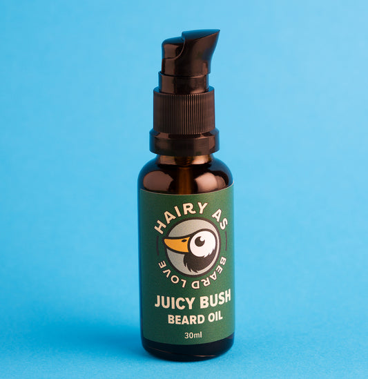 Hairy As Beard Love Beard Oil blend Juicy Bush. A 30ml amber glass bottle with a black serum pump cap. Label is green with cream coloured font. Features the Hairy As logo of a bearded duck. Blue background.