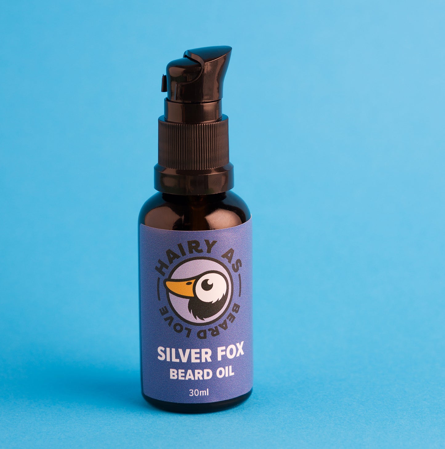 Bottle of Hairy As Silver Fox Beard Oil displayed on a blue surface, emphasizing its elegant packaging and premium quality for beard grooming.